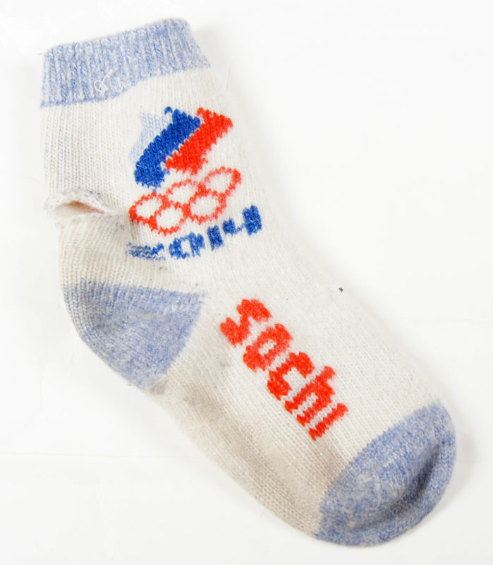 Front view of a white sock with red and blue accents. The sock says “Sochi,” and features the 2014 Sochi Winter Olympics logo.
