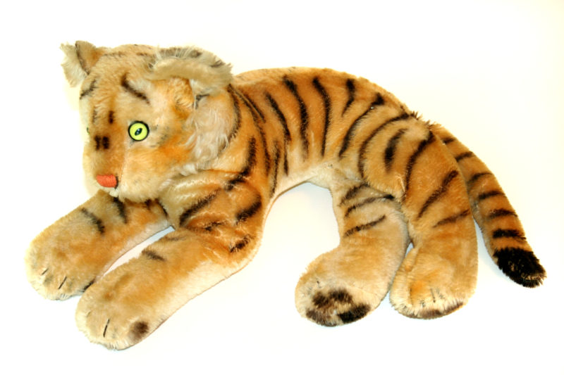 Front view of a children’s stuffed tiger. The tiger is plush and has bright green plastic eyes.