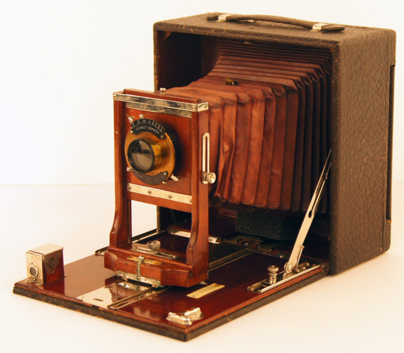 Front, diagonal view of Tennie Harris’ camera. The brown and maroon camera is shaped like a box, with a lens extending in an accordion-like fashion.