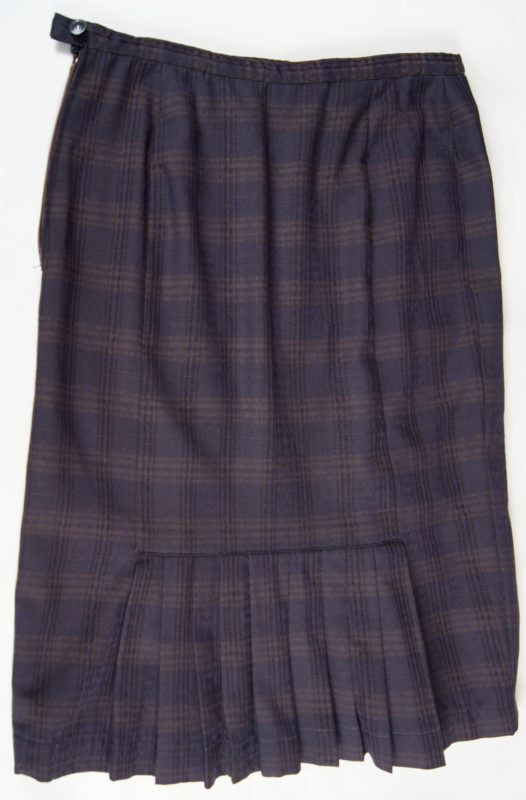 Front view of a dark skirt with a plaid pattern. The skirt features a panel of ruffles.
