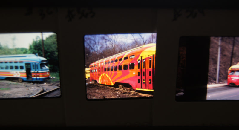 View of three photo slides featuring colorful trolleys. The slides feature different color trolleys against various landscapes.