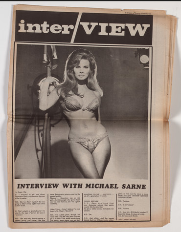 A page inside Interview magazine, volume 1, number 1, 1969, featuring a photo of a woman in lingerie leaning against film equipment.