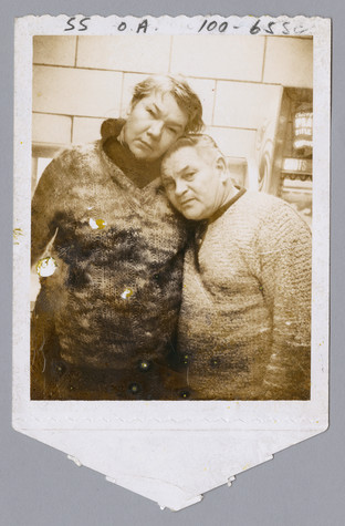 A faded, sepia-toned polaroid picture of a woman with short hair on the left resting her head on a shorter man with dark hair to the right.