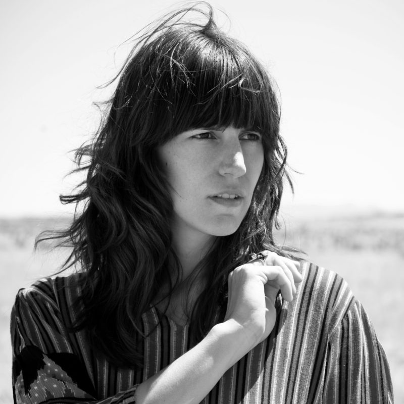 Woman with dark, windswept hair looks off into the distance.