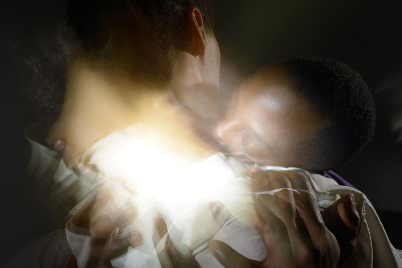 Blurred color photograph of two people embracing each other.