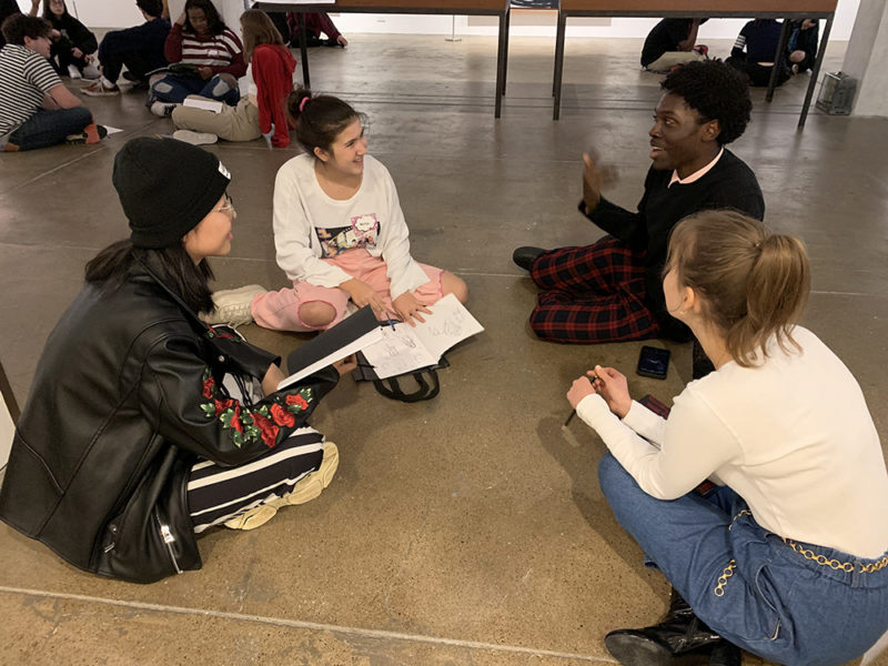 Four people having a discussion while sitting in a circle on the floor.