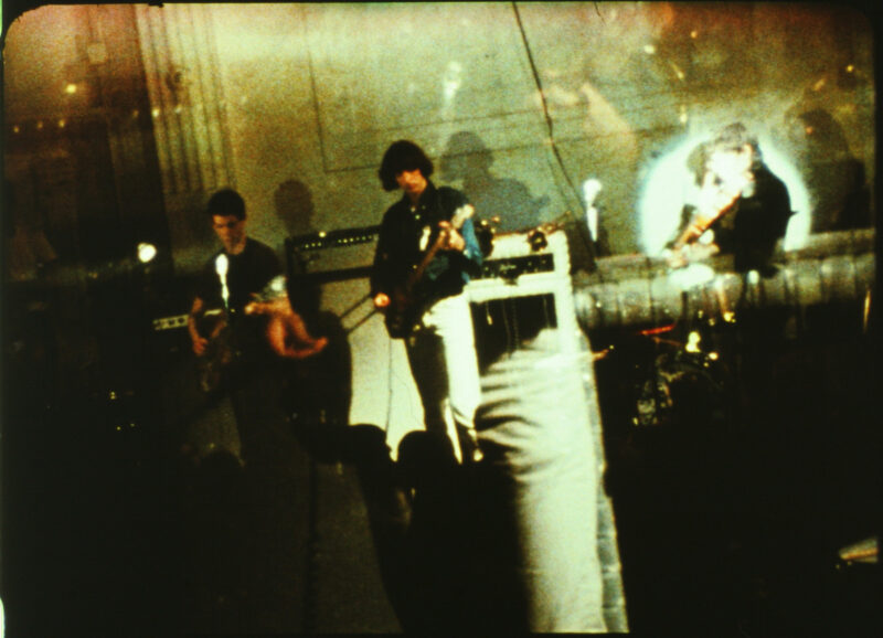 Color film still of the Velvet Underground performing on a stage.