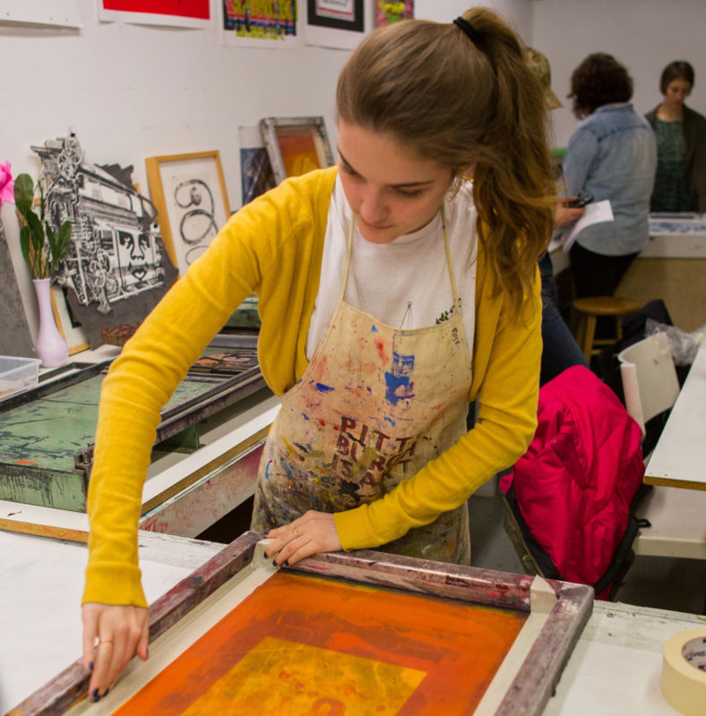 A person is silkscreening in a studio.