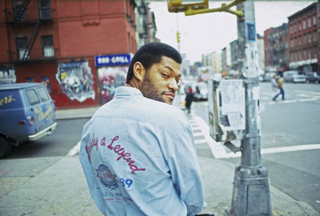 Man wearing denim jacket with lettering on the back poses for the camera.