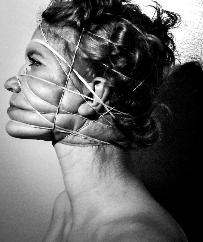 A black and white image of a person in side profile with string around their face