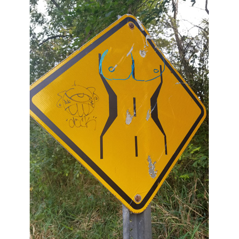 A yellow road sign with graffiti