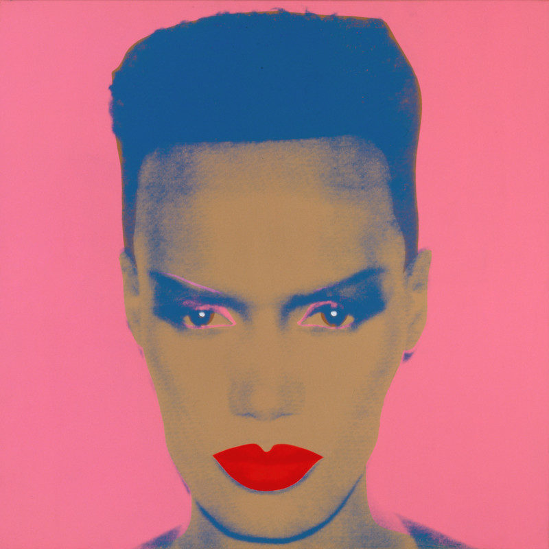 A silk-screened portrait of Grace Jones, looking forward at the viewer. Her skin is painted brown, a solid pink for the background as well as lining her eyes, and her lips are painted a solid red.