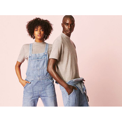 A black man and woman posing wearing the same blue denim overalls