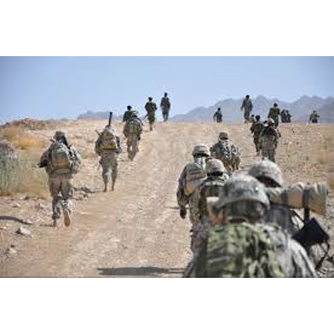 Photo of people in the military wearing camouflage and walking down a barren street