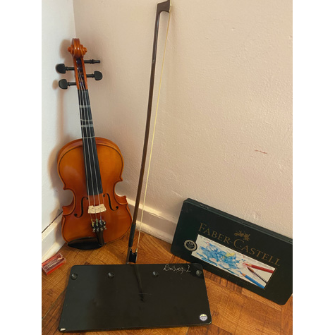A violin with a watercolor pencil set in front of it