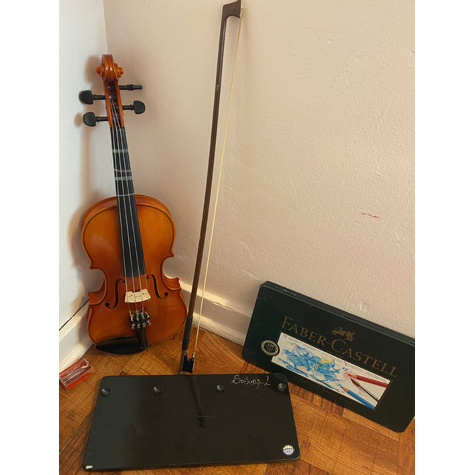 A violin with a watercolor pencil set in front of it