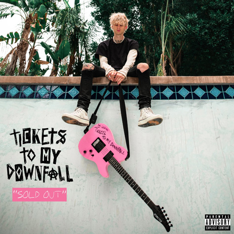 A man sitting on the wall of a pool dangling a pink guitar