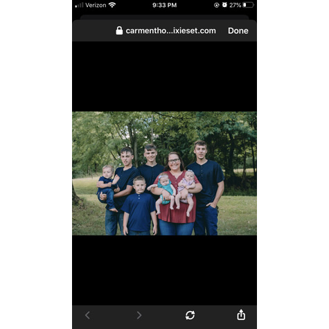 Photo of a woman holding two small children surrounded by 5 other people