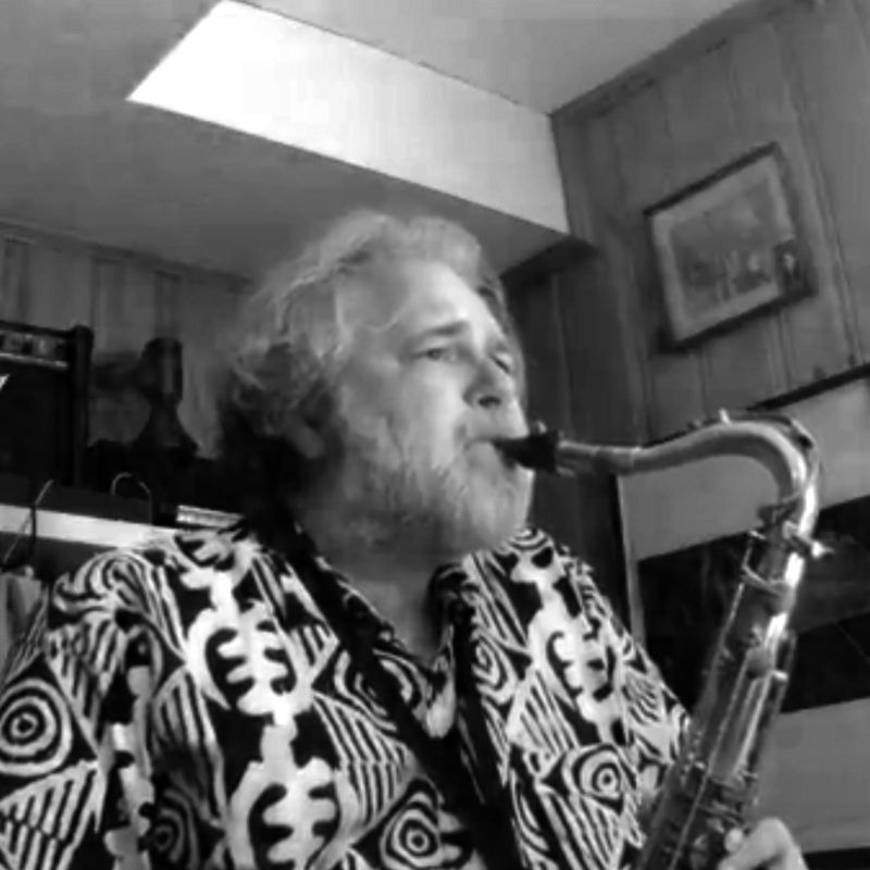 Man plays saxaphone in his basement studio.