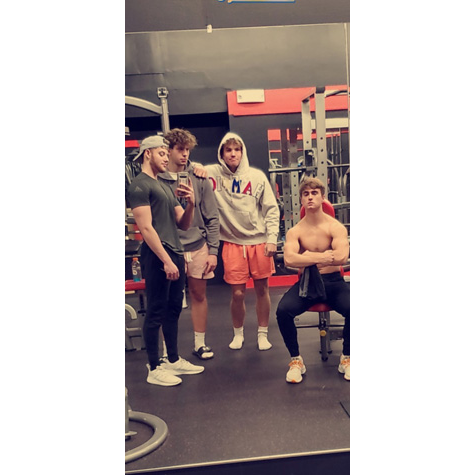 Photo of four people posing in front of a camera in a gym