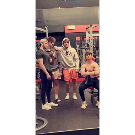 Photo of four people posing in front of a camera in a gym