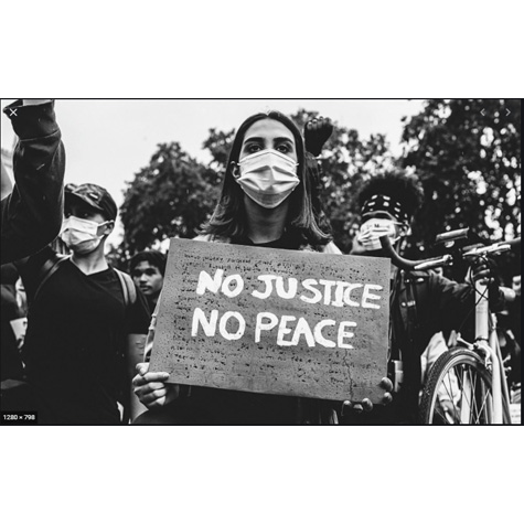 A black and white image of a person wearing a mask and holding a sign that says  no justice, no peace.