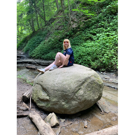 Photo of a woman sitting on a large rock in the woods