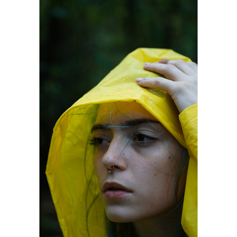 Portrait of a girl in a yellow raincoat with her hand on her head