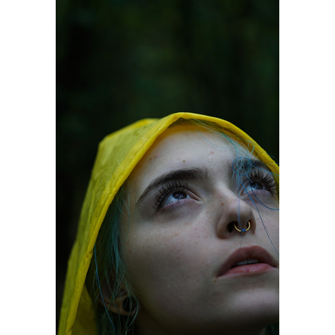 Portrait of a girl in a yellow raincoat looking up to the sky