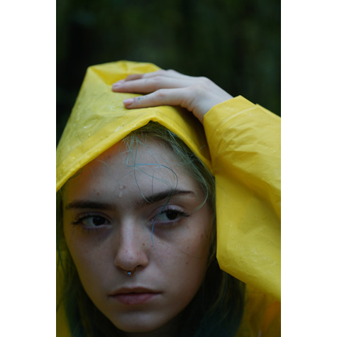 Portrait of a girl in a yellow raincoat with her hand on her head