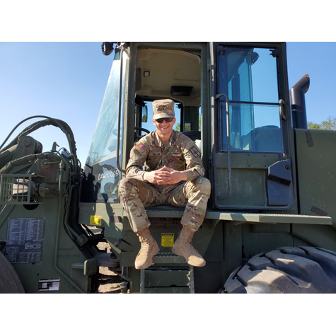 A man in a military uniform sitting on a military vehicle