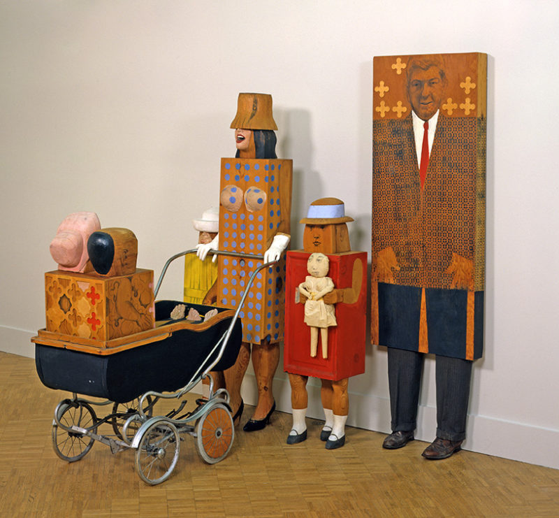 3-D sculpture of a family that includes a husband and wife, a child, and a baby in a black stroller.