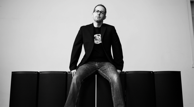 Black and white photo og a person sitting on two black blocks with a light colored wall behind them.