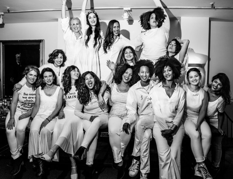 Black and white photograph of sixteen singers posing in a room and smiling.