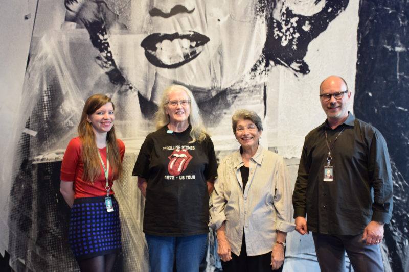 Museum educators standing in front of a Warhol image with two older women