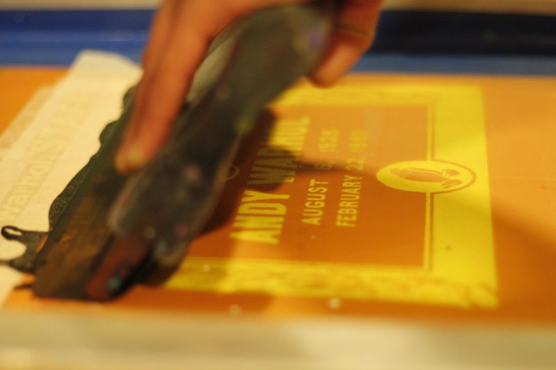 Close up of a person screenprinting a photo of Andy Warhol’s gravestone.