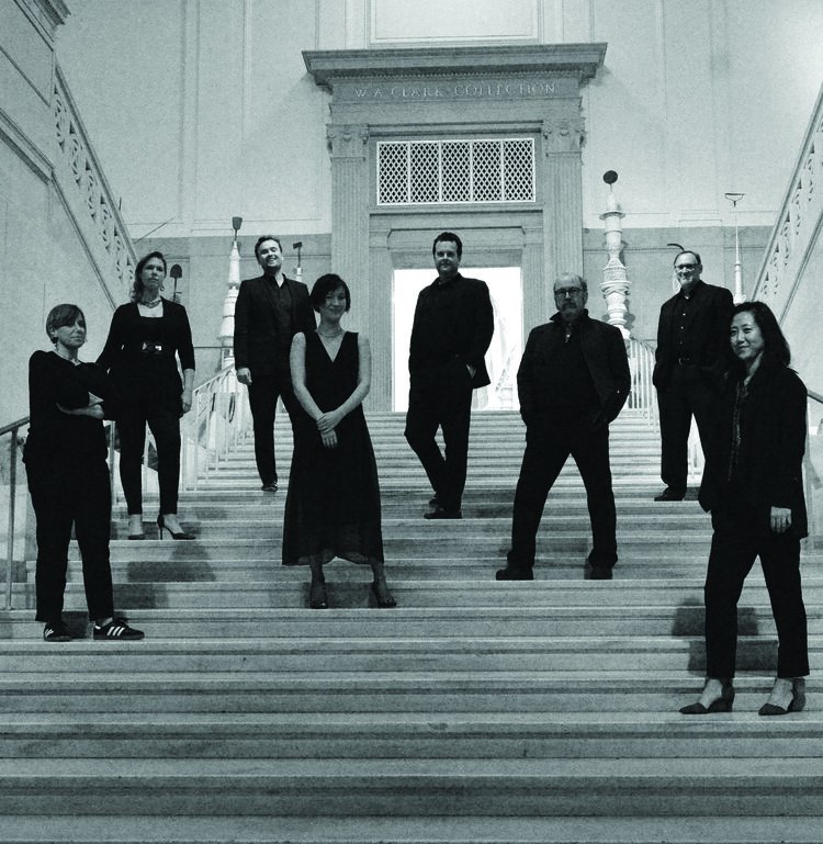 Black and white photograph of eight people standing on the steps of a building.