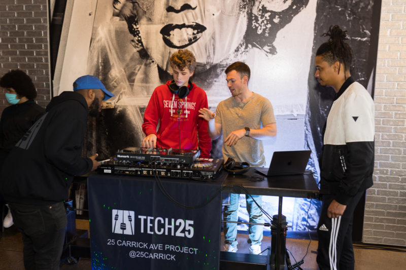 Four people standing around DJ turntables in front of a Marilyn Monroe image.