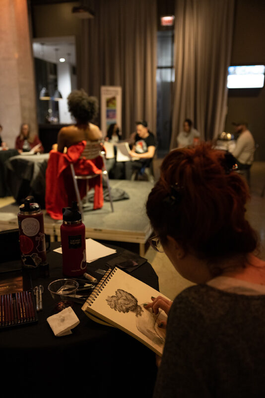 Photo of a person drawing a model in the round with out people also drawing in the entrance space of The Andy Warhol Museum.