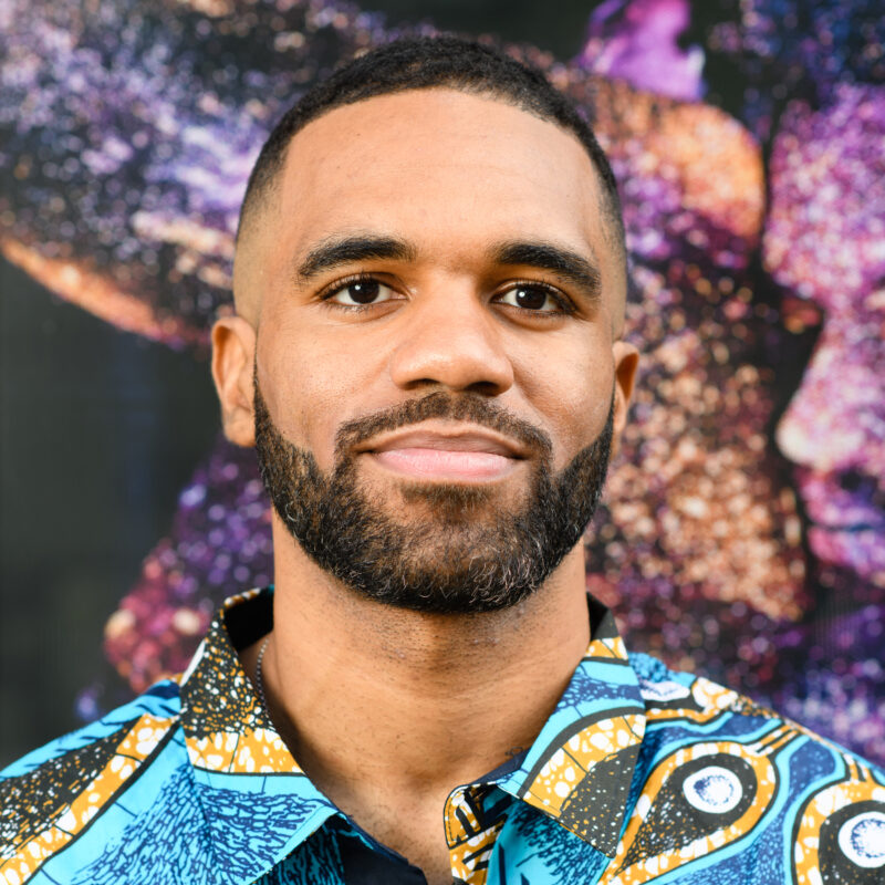 Head and shoulders portrait of man with a beard who is wearing a colorful patterned shirt.