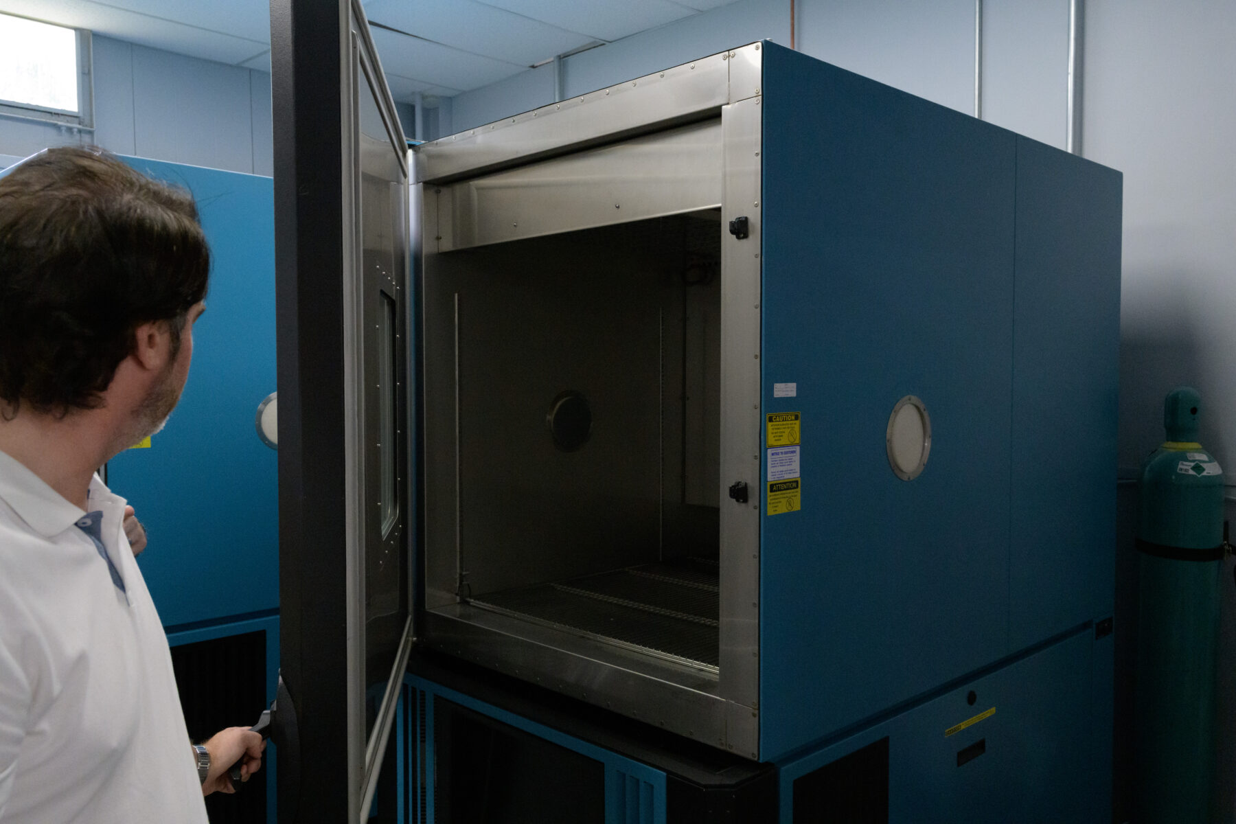 A scientist at RJ Lee Group opens the door to a Thermotron aging chamber.