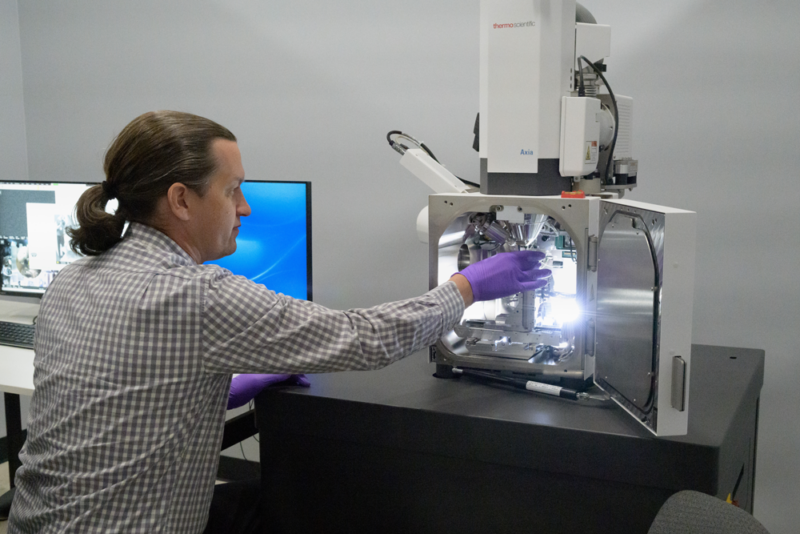 Bryan R. Bandli sits behind a digital microscope, working.