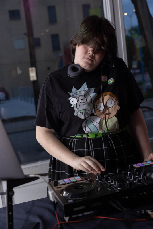 Photograph of DJ academy student using turntable while listening to headphones during Warhol youth invasion event.