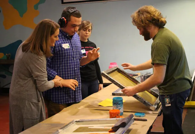 A man wearing noise-cancelling headphones makes a silkscreen print at The Andy Warhol Museum.