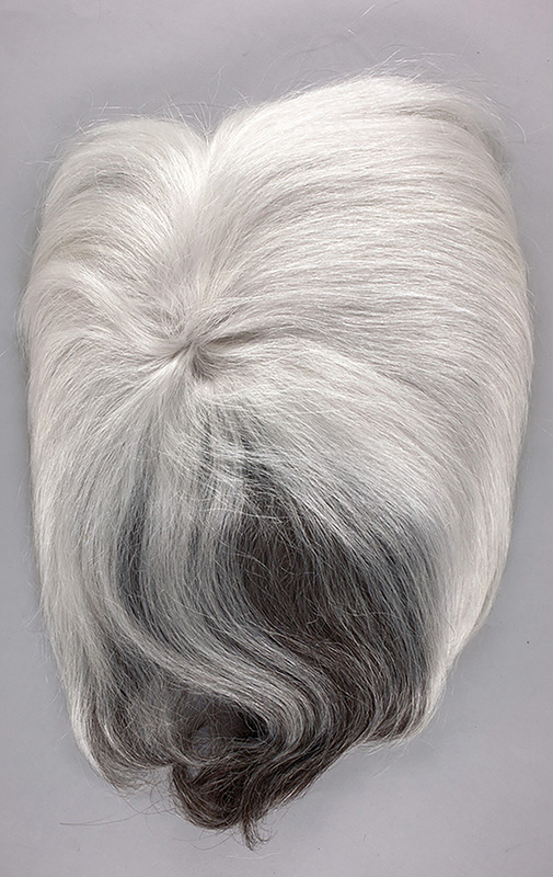 Warhol's silver and black wig on a gray surface, photographed from above