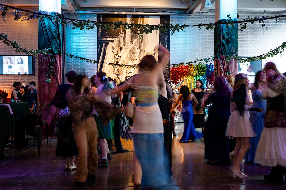 Attendees dancing in The Warhol entrance space that is all decorated, featuring artistic installations and draped greenery.