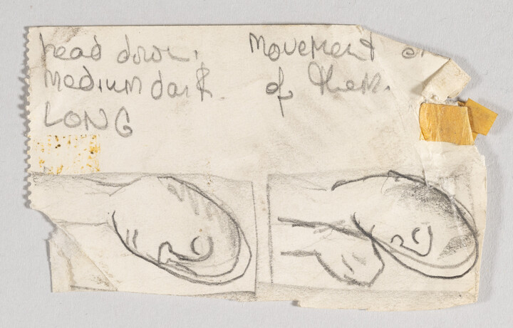 Story board sketch done on paper. Two sketches of a man laying down, one with his hand up. Text reads "head down, medium dark long" and "movement of them"