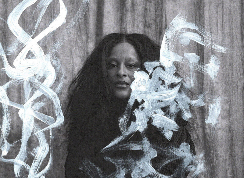 A person with long, textured hair, surrounded by artistic white brushstrokes on a gray background.